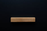 A detailed image of the Ash handle mounted on a black cabinet, capturing the texture of the wood and the stylish design from a wide perspective